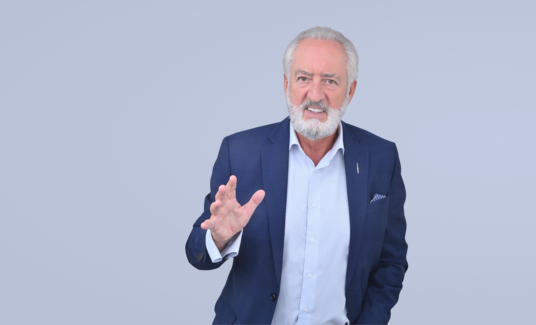 Ron Kenney speaking with an expressive hand gesture, in a blue jacket
